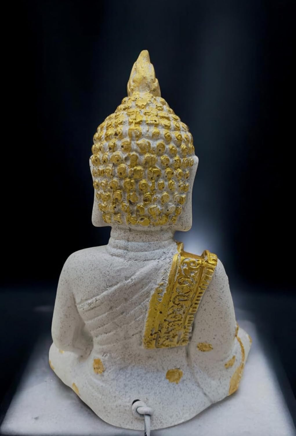 Back view of a Buddha sculpture for home with intricate details and a golden finish