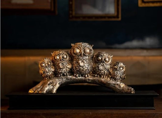 Decorative owl figurines for interiors crafted from silver-toned material, arranged on a wooden base