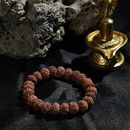 Traditional rudraksha beads accessory bracelet placed on a textured black surface with a decorative idol
